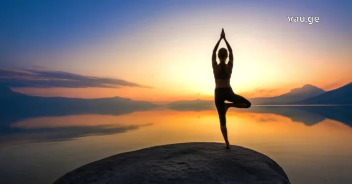 A woman standing on a mountain peak breathing fresh air, symbolizing health and freedom.