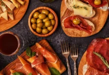 იტალიური გასტრონომია: ხელოვნება, რომელიც თეფშიდან იწყება Top view of Italian aperitivo appetizers including prosciutto, cheese, olives, and red wine on wooden boards.