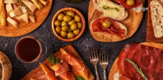 იტალიური გასტრონომია: ხელოვნება, რომელიც თეფშიდან იწყება Top view of Italian aperitivo appetizers including prosciutto, cheese, olives, and red wine on wooden boards.