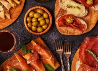 იტალიური გასტრონომია: ხელოვნება, რომელიც თეფშიდან იწყება Top view of Italian aperitivo appetizers including prosciutto, cheese, olives, and red wine on wooden boards.