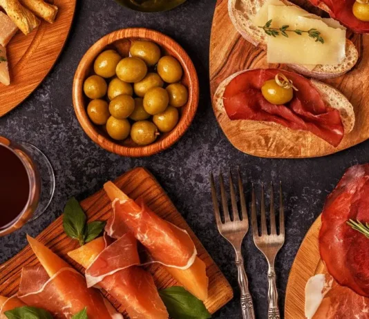 იტალიური გასტრონომია: ხელოვნება, რომელიც თეფშიდან იწყება Top view of Italian aperitivo appetizers including prosciutto, cheese, olives, and red wine on wooden boards.