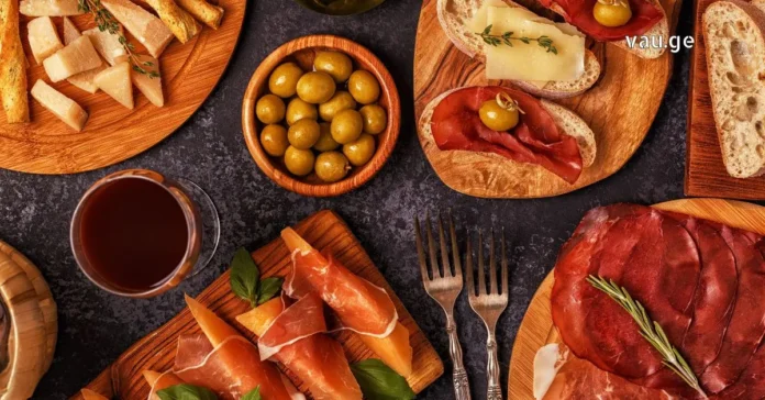 Top view of Italian aperitivo appetizers including prosciutto, cheese, olives, and red wine on wooden boards.