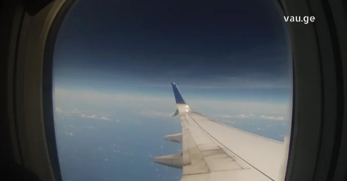 Airplane wing view from window over clouds and blue sky