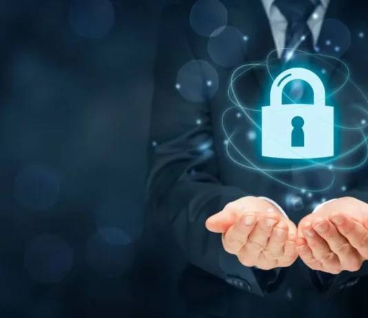 როგორ ვაქციოთ კიბერუსაფრთხოება ჩვენს ყოველდღიურობად A businessman holding a glowing digital padlock icon representing cyber security and data protection.