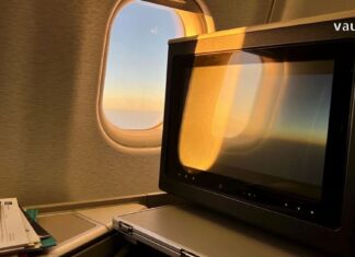 ინსტრუქცია მათთვის, ვისაც ახალი თავგადასავლები სწყურია Airplane interior with a seat-back entertainment screen and sunset view through the windows.
