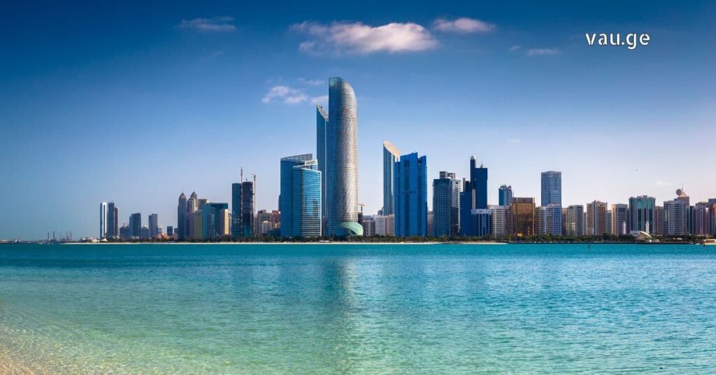 Panoramic view of Abu Dhabi skyline and modern skyscrapers reflecting in the Persian Gulf water.