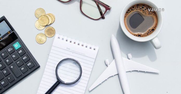 Affordable Travel Planning 2025 Flat lay of a travel planning workspace with a toy airplane, calculator, coins, and a cup of coffee.