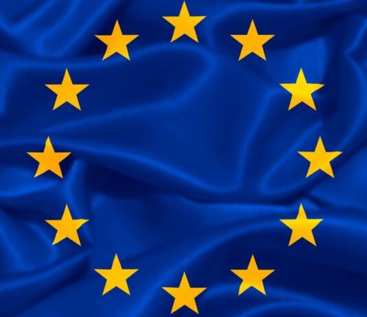 ევროპული თავისუფლების გზა: 2017 წლამდელი ბარიერები და 2026 წლის გაურკვევლობა Waving European Union flag with blue fabric and yellow stars, representing Georgia's visa-free travel and European integration.