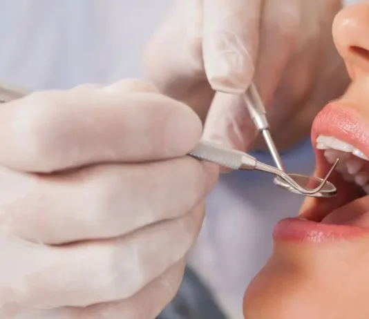 ღიმილი, როგორც ხელოვნება: თანამედროვე სტომატოლოგიის მიღწევები A professional dentist performing a dental examination on a patient using specialized tools.