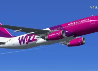 ვიმოგზაუროთ ჭკვიანურად – Wizz Air Georgia A side profile view of a Wizz Air Airbus A320 aircraft with its white, purple, and magenta livery, parked on the airport tarmac under a clear blue sky.